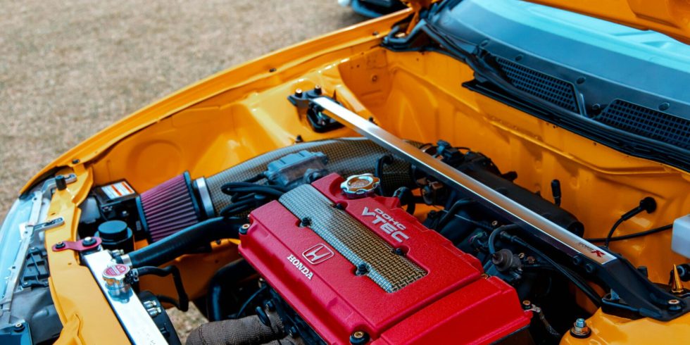 Vivid yellow car with red engine on display at outdoor event.